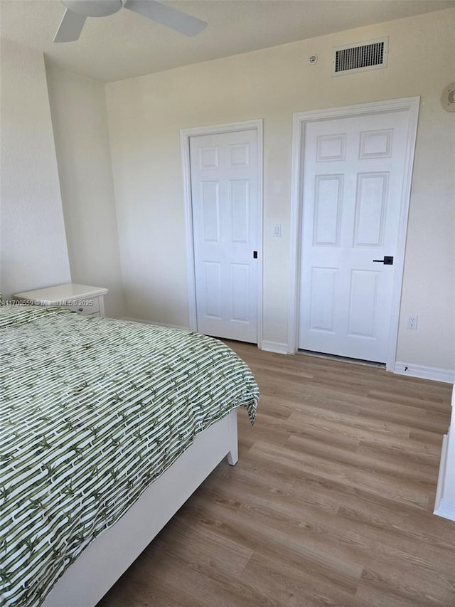 bedroom featuring visible vents, baseboards, ceiling fan, and light wood finished floors