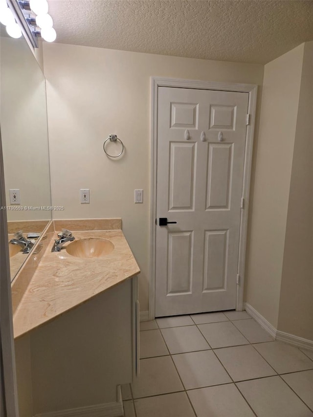 bathroom with tile patterned floors, a textured ceiling, vanity, and baseboards