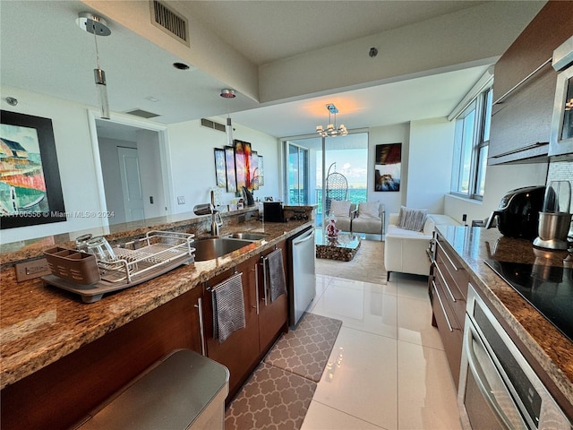 kitchen featuring sink, stainless steel appliances, an inviting chandelier, dark tile patterned floors, and decorative light fixtures