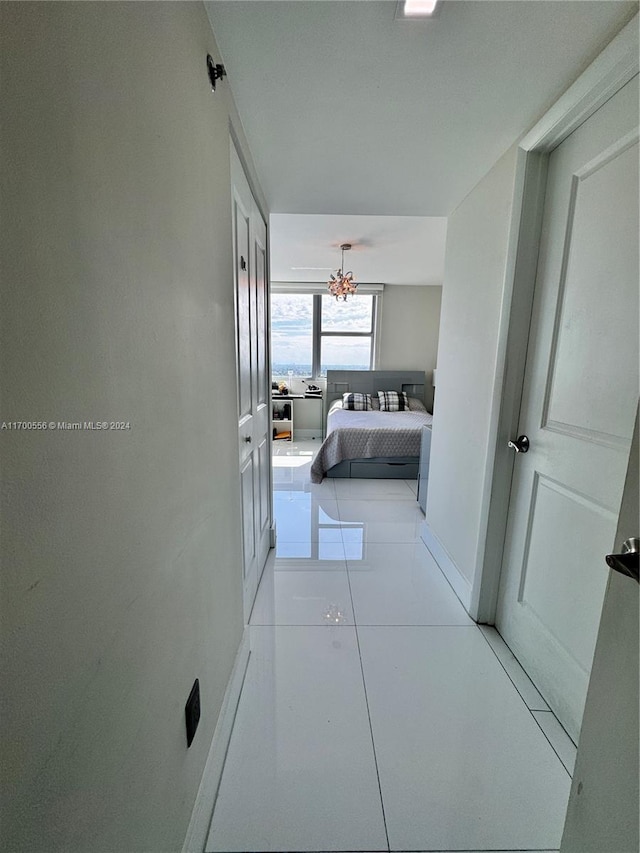 corridor featuring light tile patterned floors and a notable chandelier