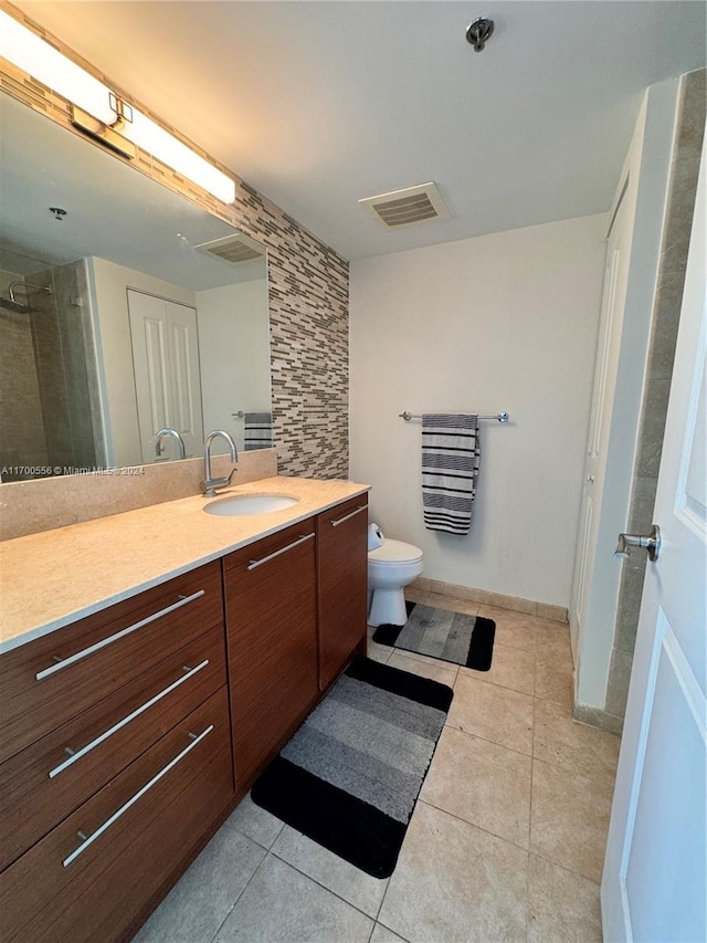 bathroom with tile patterned flooring, vanity, a shower with door, and toilet