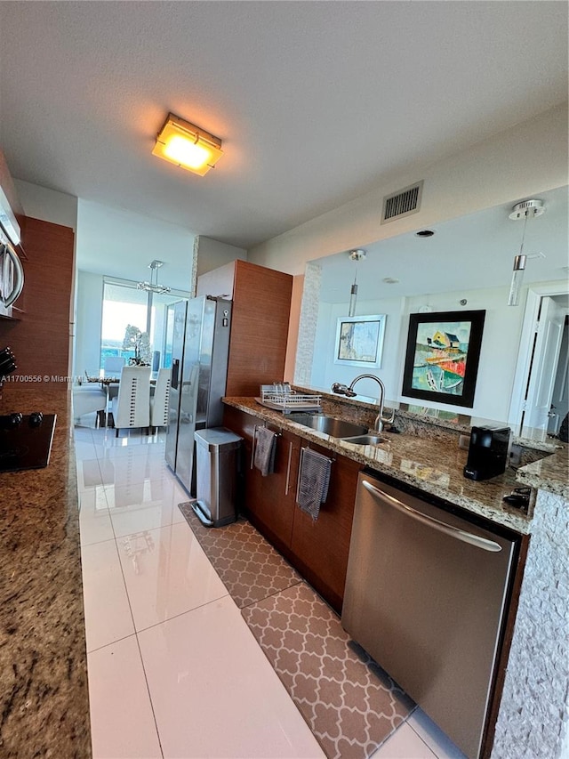 kitchen featuring dark tile patterned floors, sink, hanging light fixtures, and stainless steel appliances