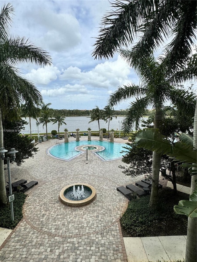 view of swimming pool featuring a water view and a hot tub