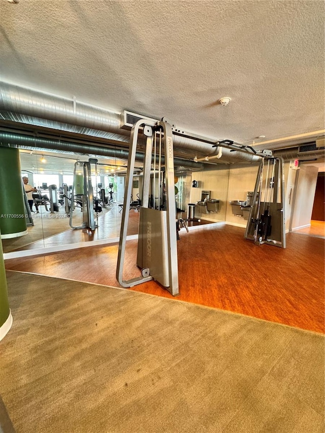 exercise room with hardwood / wood-style floors and a textured ceiling