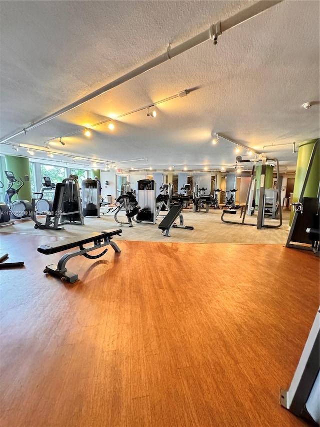 workout area with light wood-type flooring and a textured ceiling