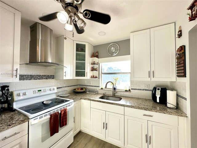 kitchen with backsplash, white cabinets, sink, white electric stove, and wall chimney exhaust hood