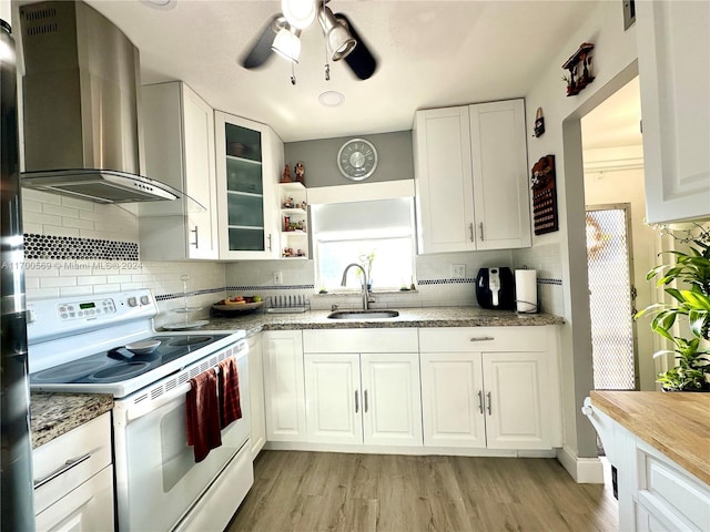 kitchen featuring wall chimney range hood, white cabinetry, white electric stove, and sink