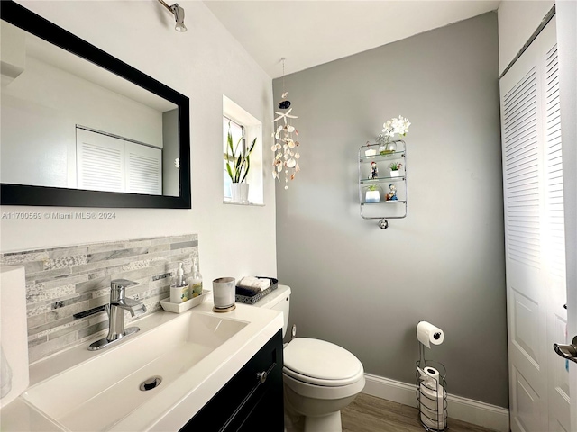 bathroom featuring hardwood / wood-style floors, vanity, toilet, and decorative backsplash