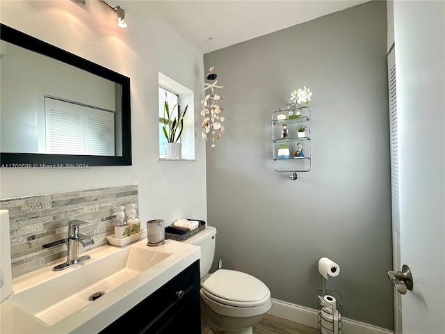 bathroom featuring hardwood / wood-style floors, vanity, tasteful backsplash, and toilet