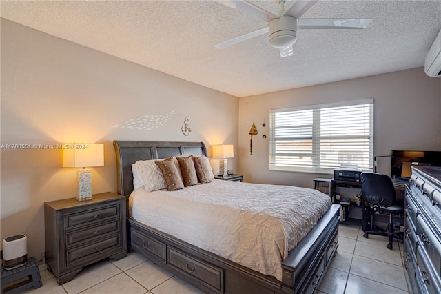 bedroom featuring ceiling fan, light tile patterned floors, and a textured ceiling