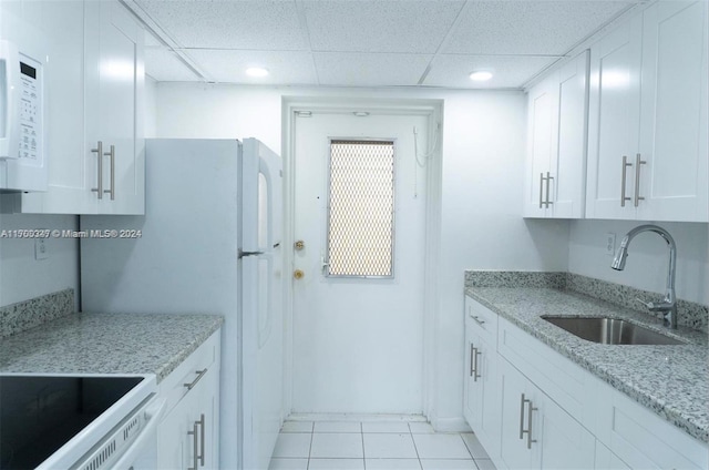 kitchen with light stone counters, sink, white cabinets, and stove