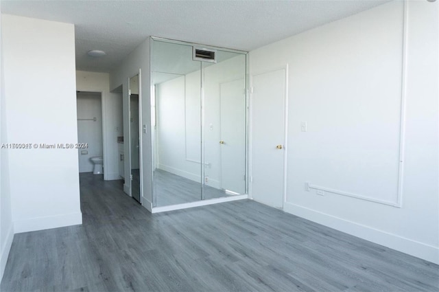 unfurnished bedroom featuring a closet, dark hardwood / wood-style flooring, and a textured ceiling