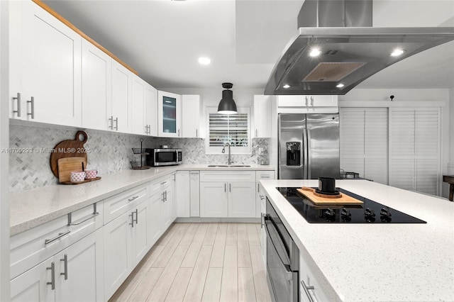 kitchen featuring appliances with stainless steel finishes, sink, island range hood, white cabinets, and tasteful backsplash