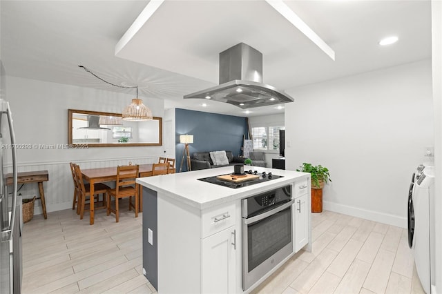 kitchen with white cabinetry, stainless steel oven, washing machine and clothes dryer, black electric cooktop, and island exhaust hood