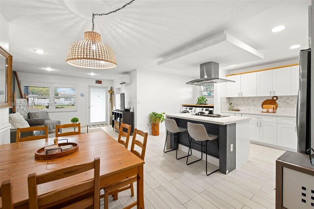 dining room with a wall mounted AC and light hardwood / wood-style floors