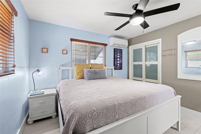 bedroom with ceiling fan, light hardwood / wood-style floors, multiple windows, and a wall mounted air conditioner