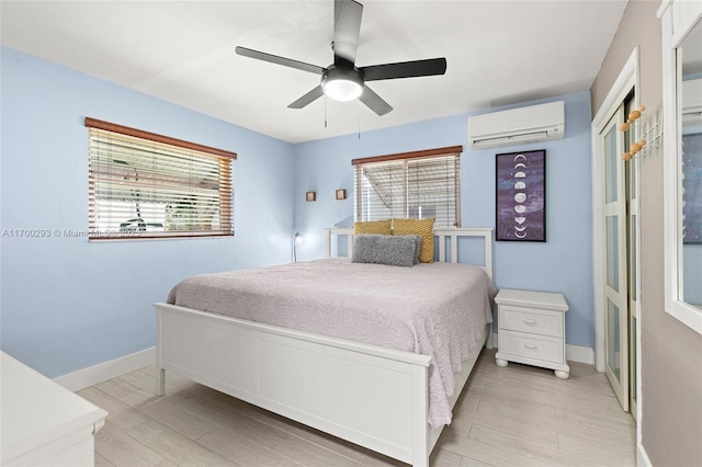 bedroom featuring an AC wall unit, multiple windows, ceiling fan, and light hardwood / wood-style flooring