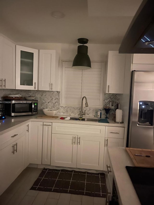 kitchen with appliances with stainless steel finishes, backsplash, sink, white cabinetry, and range hood