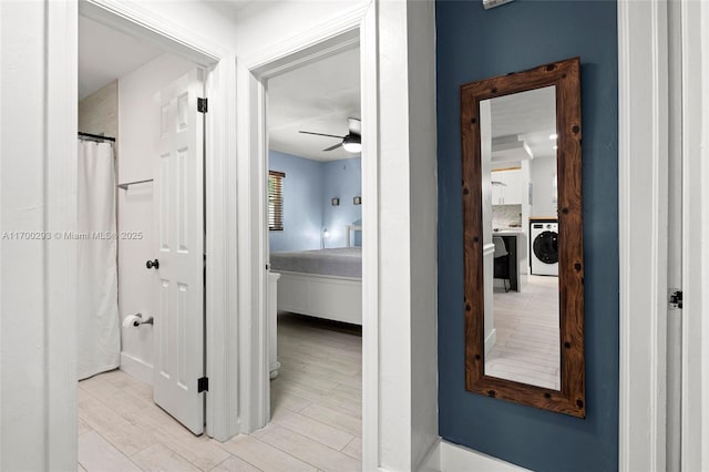 hallway with light wood-type flooring and washer / clothes dryer