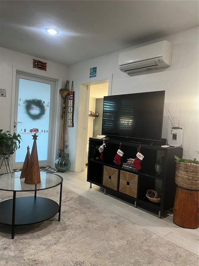 living room with a wall mounted AC and light hardwood / wood-style floors