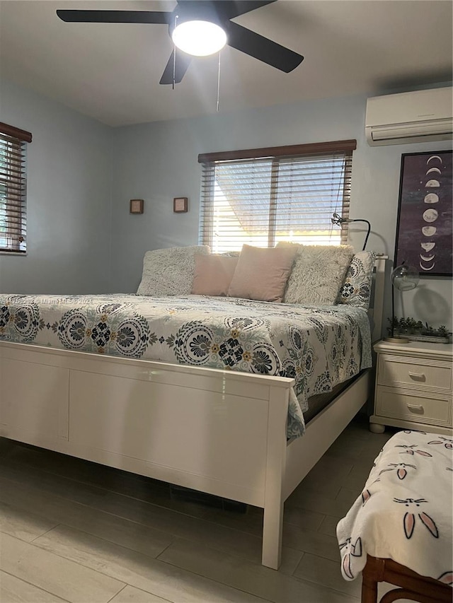 bedroom featuring wood-type flooring, a wall unit AC, and ceiling fan