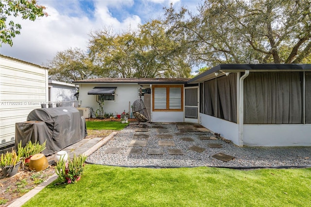 back of house with a patio area, a yard, and a sunroom