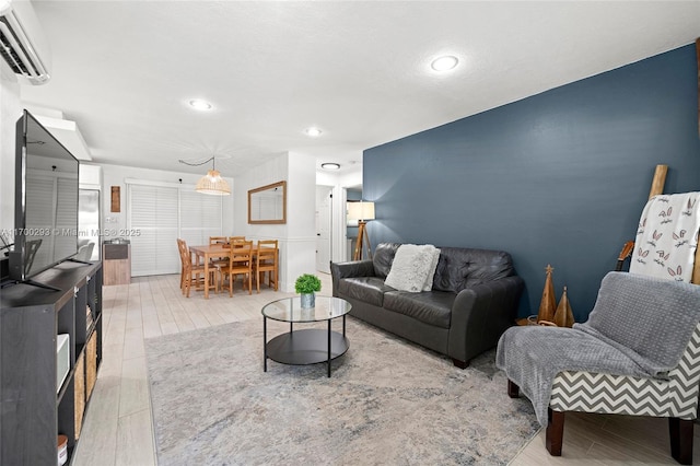 living room with a wall unit AC and light hardwood / wood-style flooring