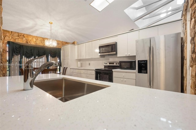 kitchen with white cabinets, hanging light fixtures, sink, light stone countertops, and appliances with stainless steel finishes