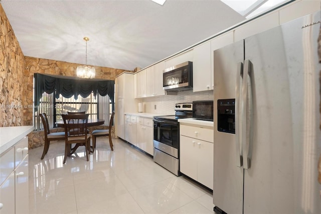 kitchen with appliances with stainless steel finishes, white cabinetry, pendant lighting, and a notable chandelier