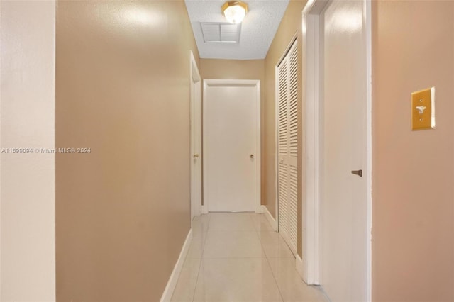 hallway with light tile patterned flooring and a textured ceiling