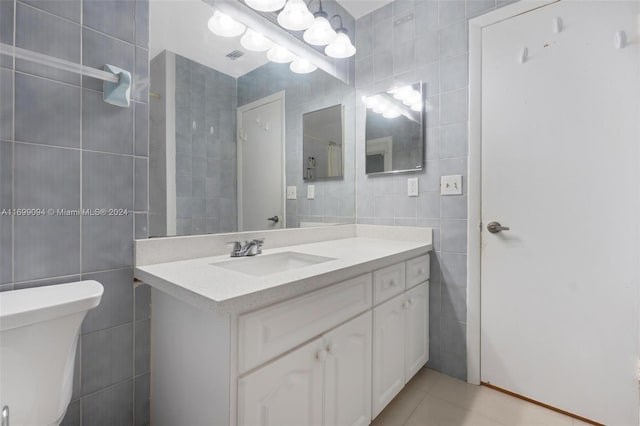 bathroom featuring tile patterned floors, vanity, tile walls, and toilet