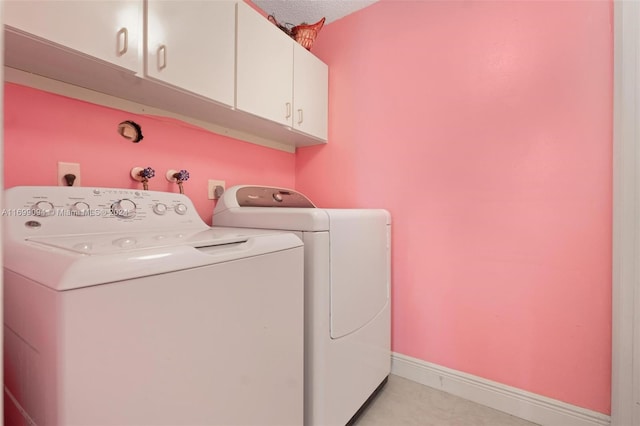 laundry room featuring separate washer and dryer, cabinets, and a textured ceiling