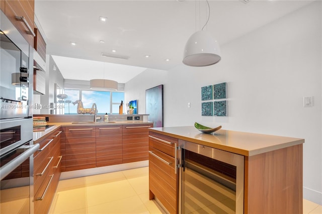 kitchen featuring pendant lighting, light tile patterned floors, sink, and wine cooler