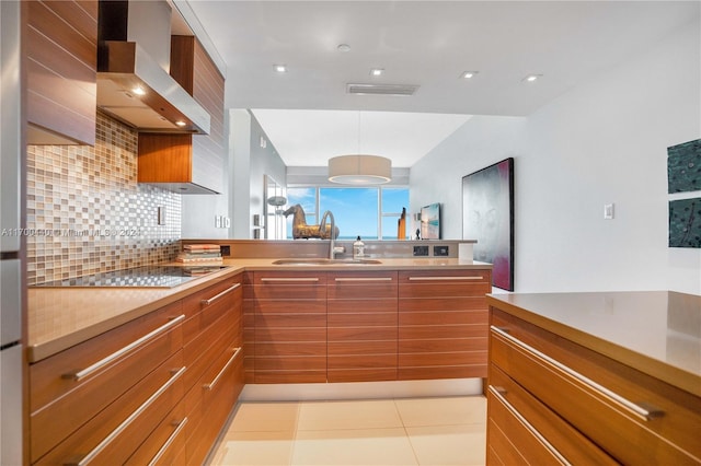 kitchen with sink, hanging light fixtures, wall chimney range hood, black electric stovetop, and light tile patterned floors