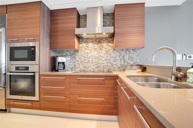 kitchen featuring sink, wall chimney exhaust hood, decorative backsplash, light tile patterned flooring, and stainless steel appliances