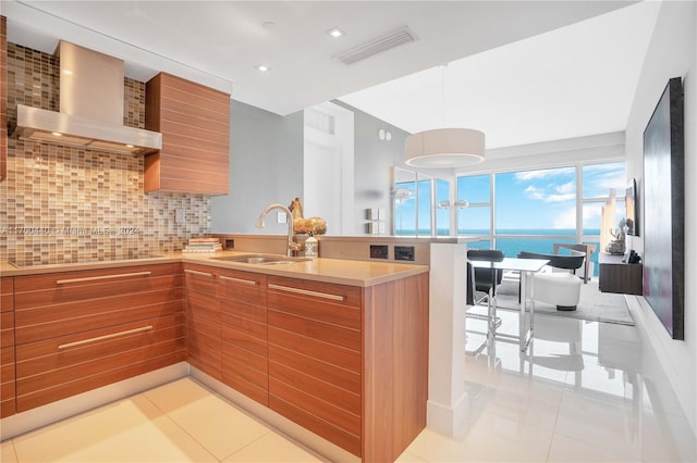 kitchen featuring sink, wall chimney range hood, decorative backsplash, black electric stovetop, and a water view