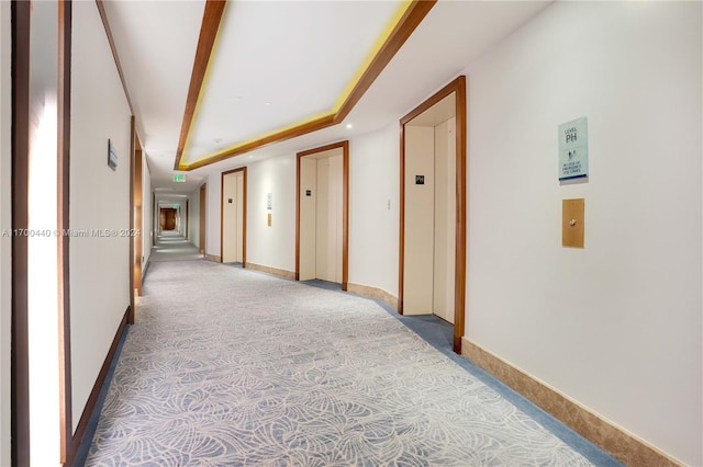 corridor featuring light carpet, elevator, and beamed ceiling