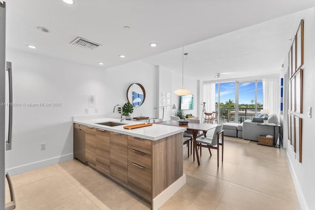 kitchen featuring kitchen peninsula, decorative light fixtures, light tile patterned flooring, and sink