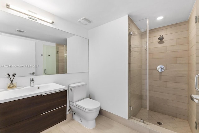 bathroom featuring vanity, toilet, and a shower with shower door