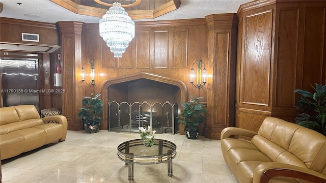 living area with a textured ceiling, wood walls, visible vents, and a notable chandelier