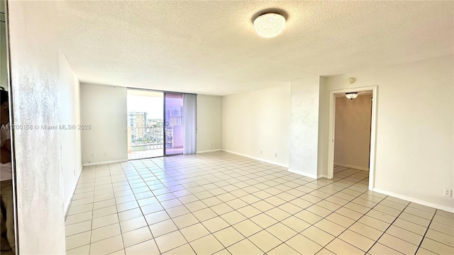 spare room with floor to ceiling windows, a textured ceiling, baseboards, and light tile patterned floors