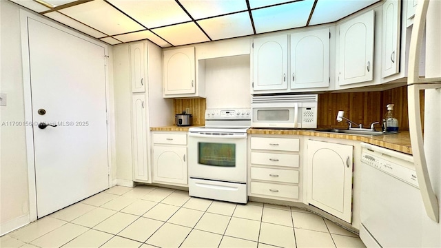 kitchen featuring sink, white appliances, a paneled ceiling, and light tile patterned floors