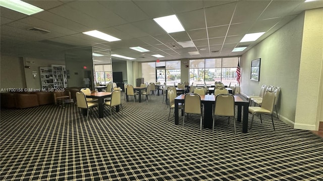 dining area with baseboards, visible vents, a paneled ceiling, a textured wall, and carpet floors