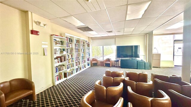 carpeted dining space with a drop ceiling