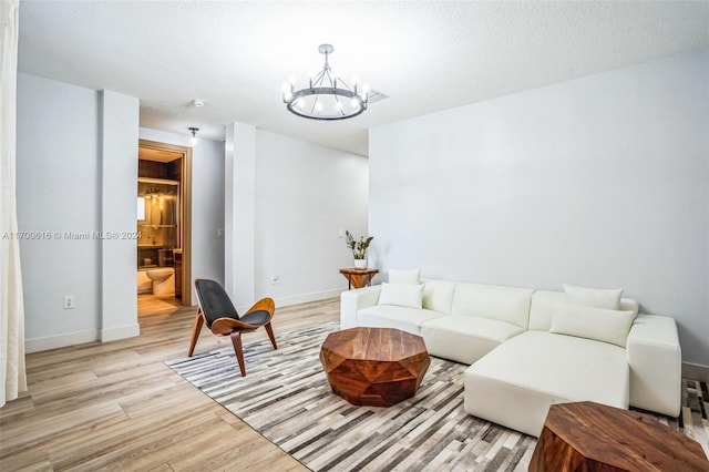 living room featuring light wood-type flooring, a textured ceiling, and an inviting chandelier