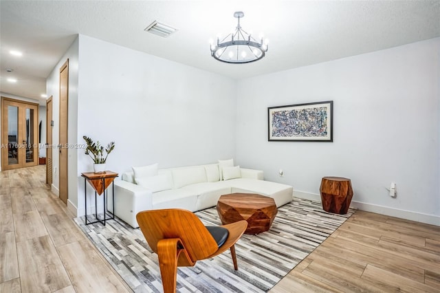 living room with a notable chandelier, a textured ceiling, and light hardwood / wood-style flooring