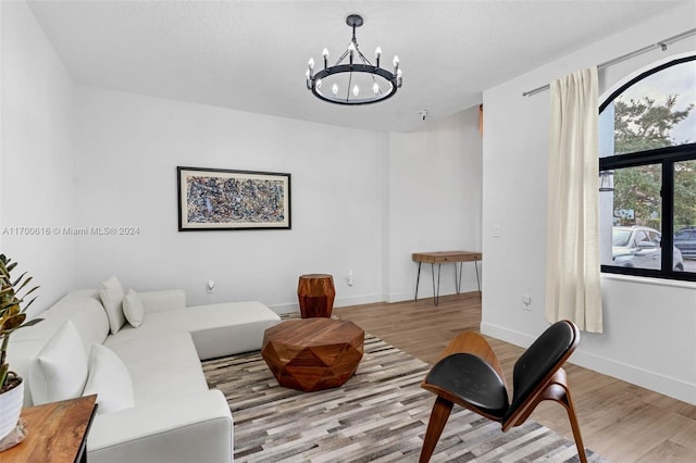 living room featuring a chandelier, light hardwood / wood-style floors, and a textured ceiling