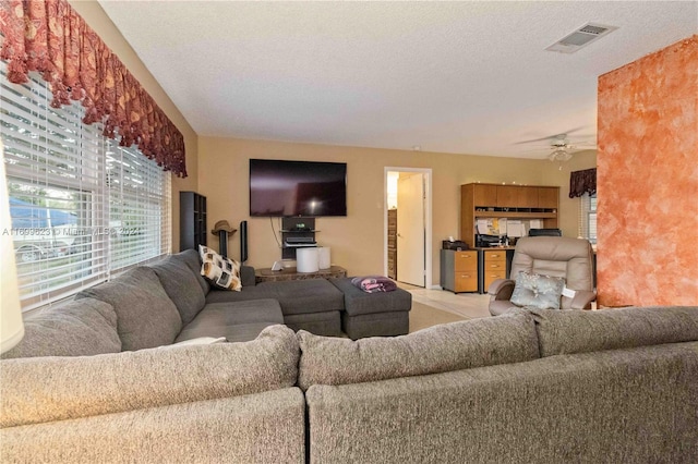 living room featuring ceiling fan and a textured ceiling