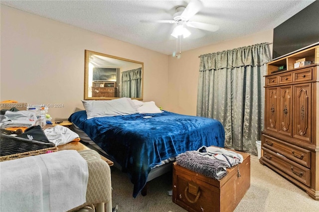 bedroom with a textured ceiling, light colored carpet, and ceiling fan