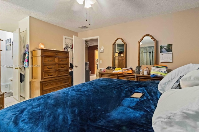 tiled bedroom featuring ceiling fan, a textured ceiling, and ensuite bath